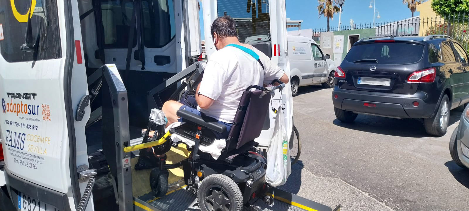 Fotografía en la que se ve a una pesona en silla de ruedas accediendo a un vehiculo de transporte adaptado.