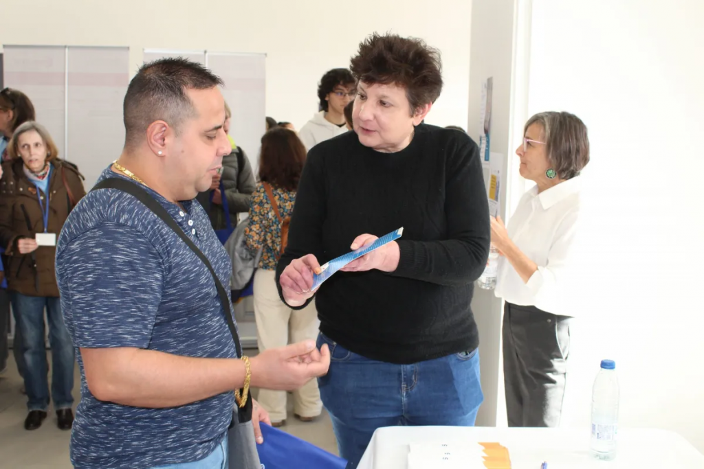 Fotografía en la que se puede ver al personal ayudando a los que han asistido a la feria de empleo, así como indicandoles las actividades escritas en un folleto.